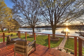 A wooden deck with outdoor furniture, a lake view, and a sunset. - Sandy Shore (Mooresville)