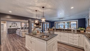 Cocina amplia con una isla grande, armarios blancos y vistas al exterior.