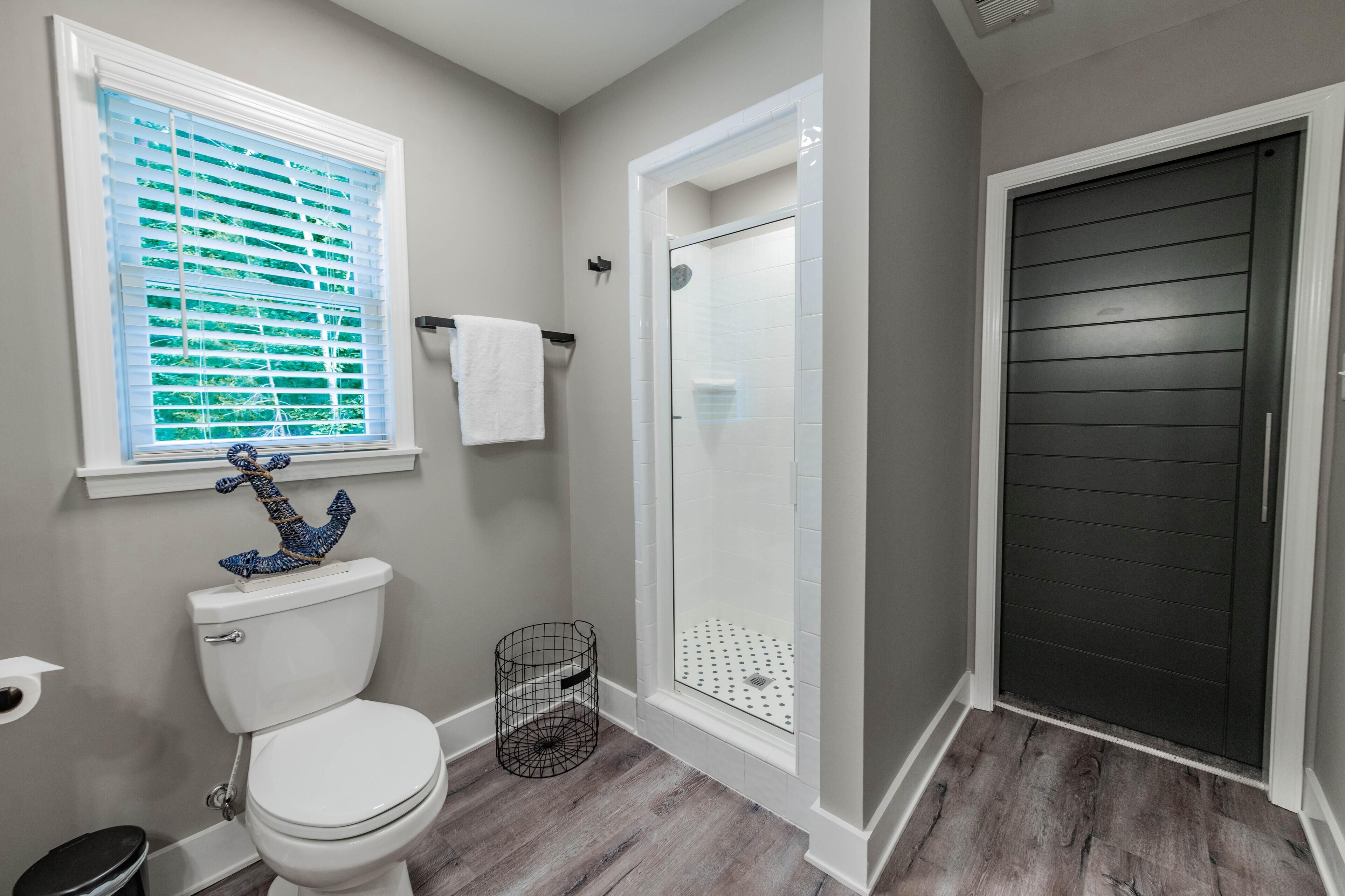 Une salle de bain avec des toilettes, une douche et une fenêtre avec des stores.