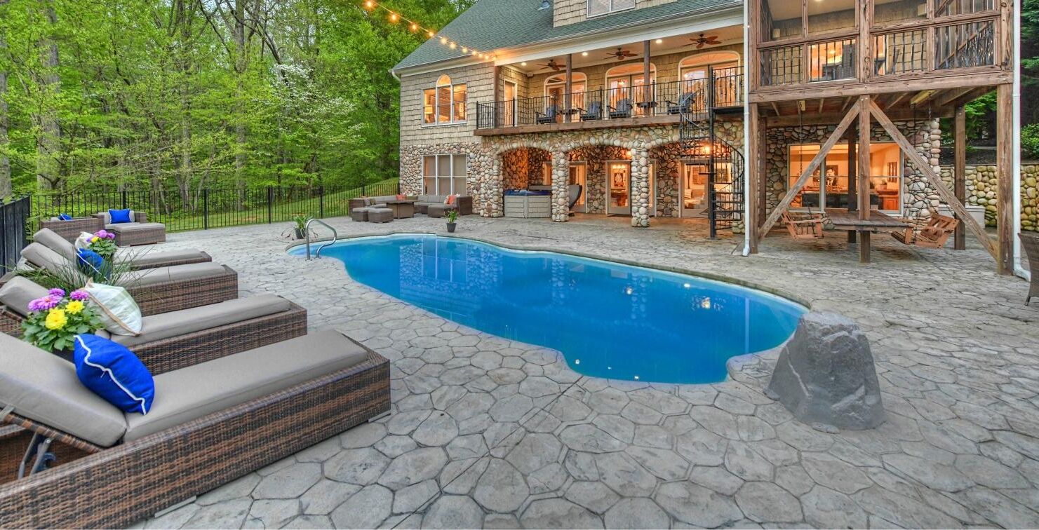 A stone house with a swimming pool, outdoor seating, and a balcony.