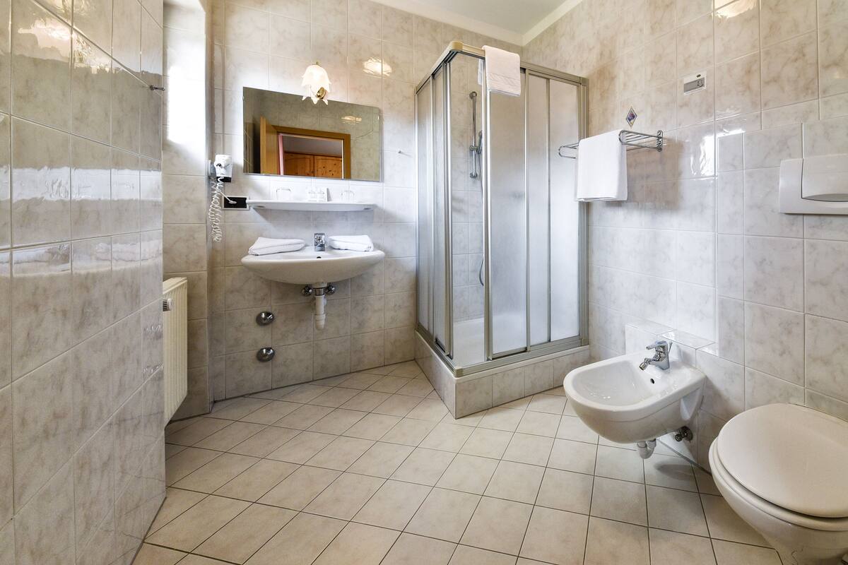 A modern bathroom with a shower, sink, bidet, and toilet.