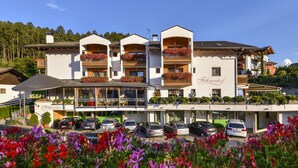 Ein Hotel mit mehreren Balkonen, einem Restaurant und einem Parkplatz.