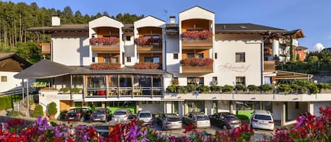 Un hotel con varios balcones, un restaurante y un estacionamiento.