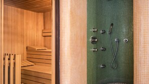 Eine Sauna mit Holzbänken und einer gefliesten Wand mit Brause.