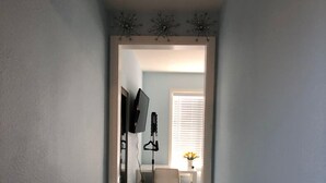 A narrow hallway with a desk and chair, a television, and a window with blinds. - Elegant charming unit close to everything (San Mateo)