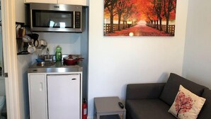 A compact living space with a kitchenette, a sofa, and a painting on the wall. - Elegant charming unit close to everything (San Mateo)