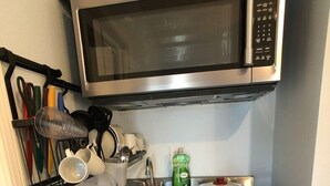 A compact kitchen with a built-in microwave, a sink, and a stove. - Elegant charming unit close to everything (San Mateo)