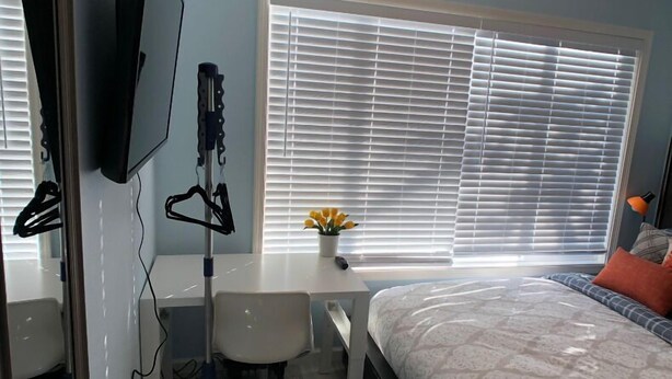 A bedroom with a bed, a desk, a chair, a TV, and a window with blinds. - Elegant charming unit close to everything (San Mateo)