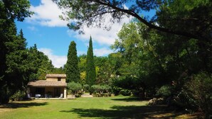 A house with a tiled roof, surrounded by a well-maintained lawn and various trees. - Stone House near Châteauneuf-du-Pape Vineyards (Bédarrides)
