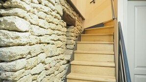 A staircase with a stone wall on one side and a wooden handrail on the other. - Stone House near Châteauneuf-du-Pape Vineyards (Bédarrides)