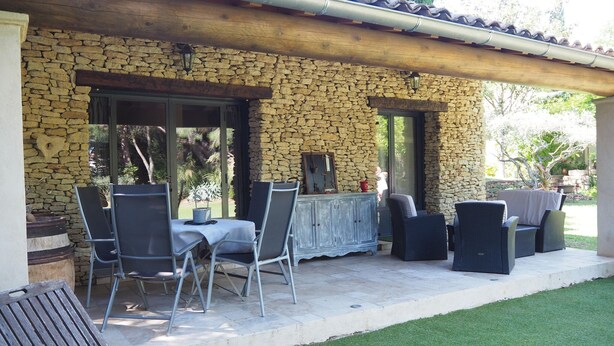 A stone exterior with a covered patio area featuring outdoor furniture and a dining table. - Stone House near Châteauneuf-du-Pape Vineyards (Bédarrides)