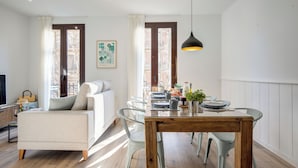 A modern living room with a sofa, a dining table with chairs, and a TV. - LUCASLAND (Barcelona)