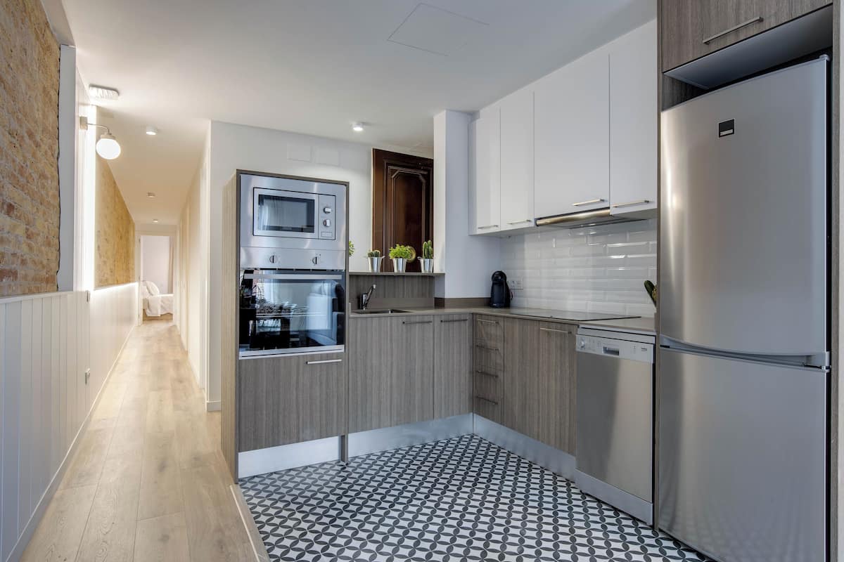Una cocina moderna con electrodomésticos de acero inoxidable, armarios de madera y piso estampado.