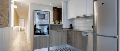 A modern kitchen with stainless steel appliances, wooden cabinets, and a patterned floor.
