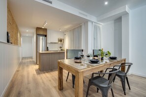 Una cocina moderna con una mesa de comedor de madera, sillas negras y una isla integrada con microondas y horno.