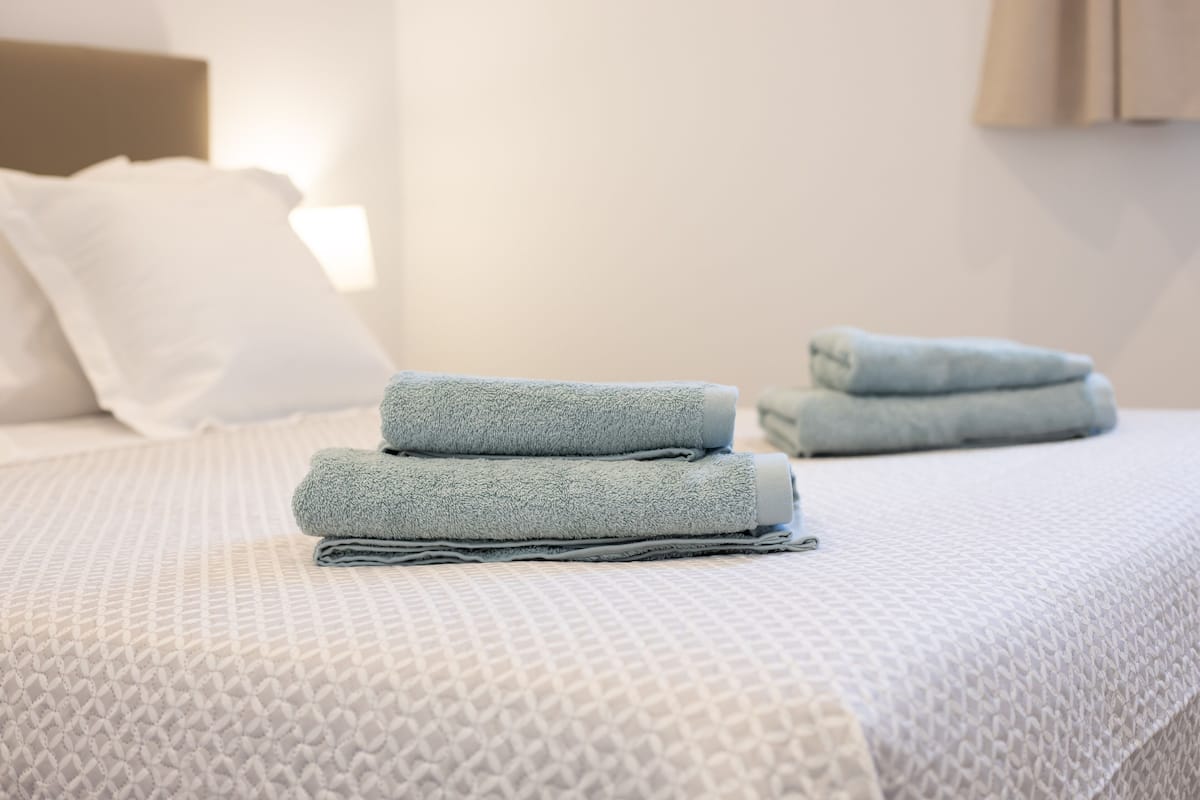 Una cama bien hecha con una colcha estampada y toallas dobladas.