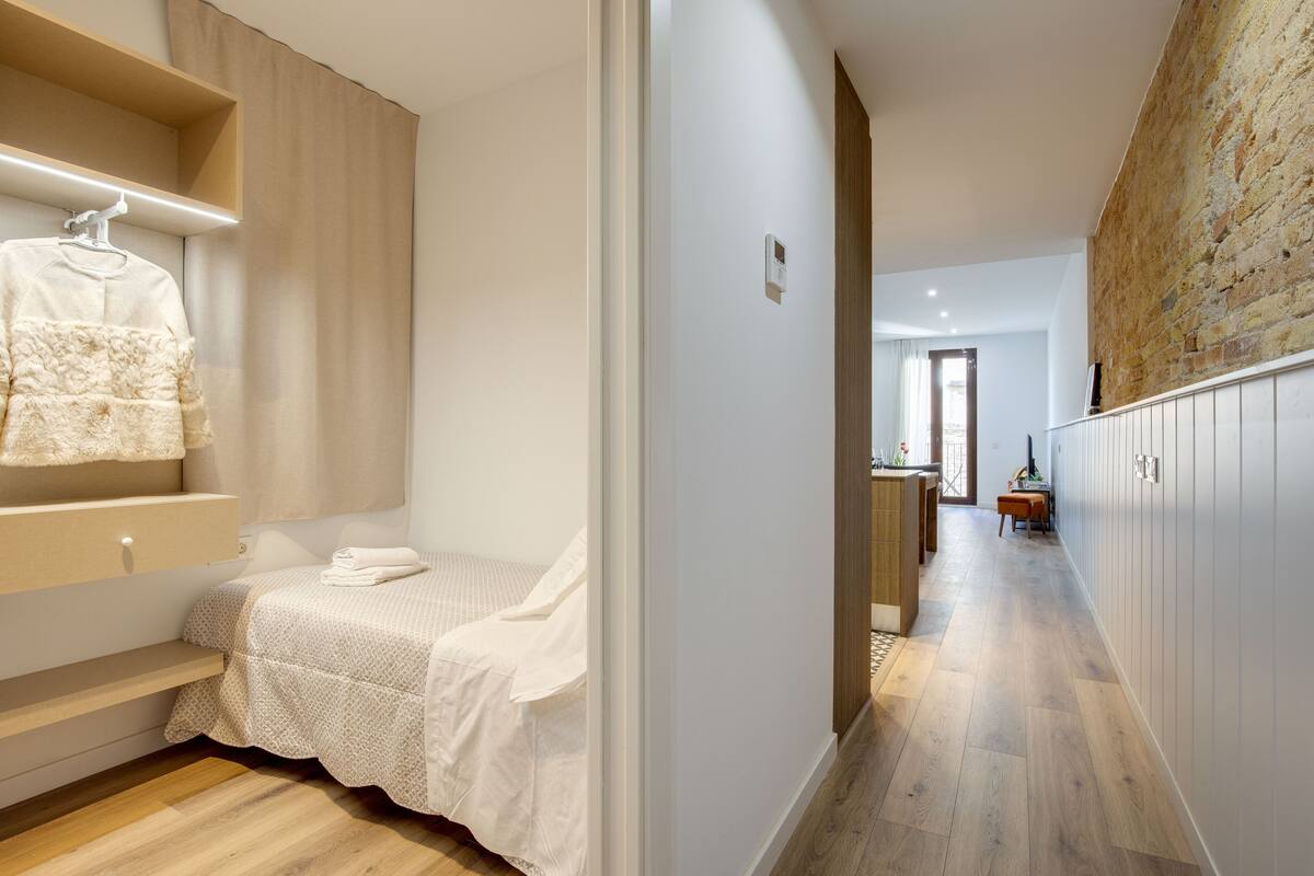 Una habitación de hotel moderna con una cama, una pequeña zona de estar y vistas al pasillo.
