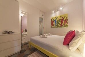 Relax in a serene space with a large bed, colorful artwork, and a stylish dresser.