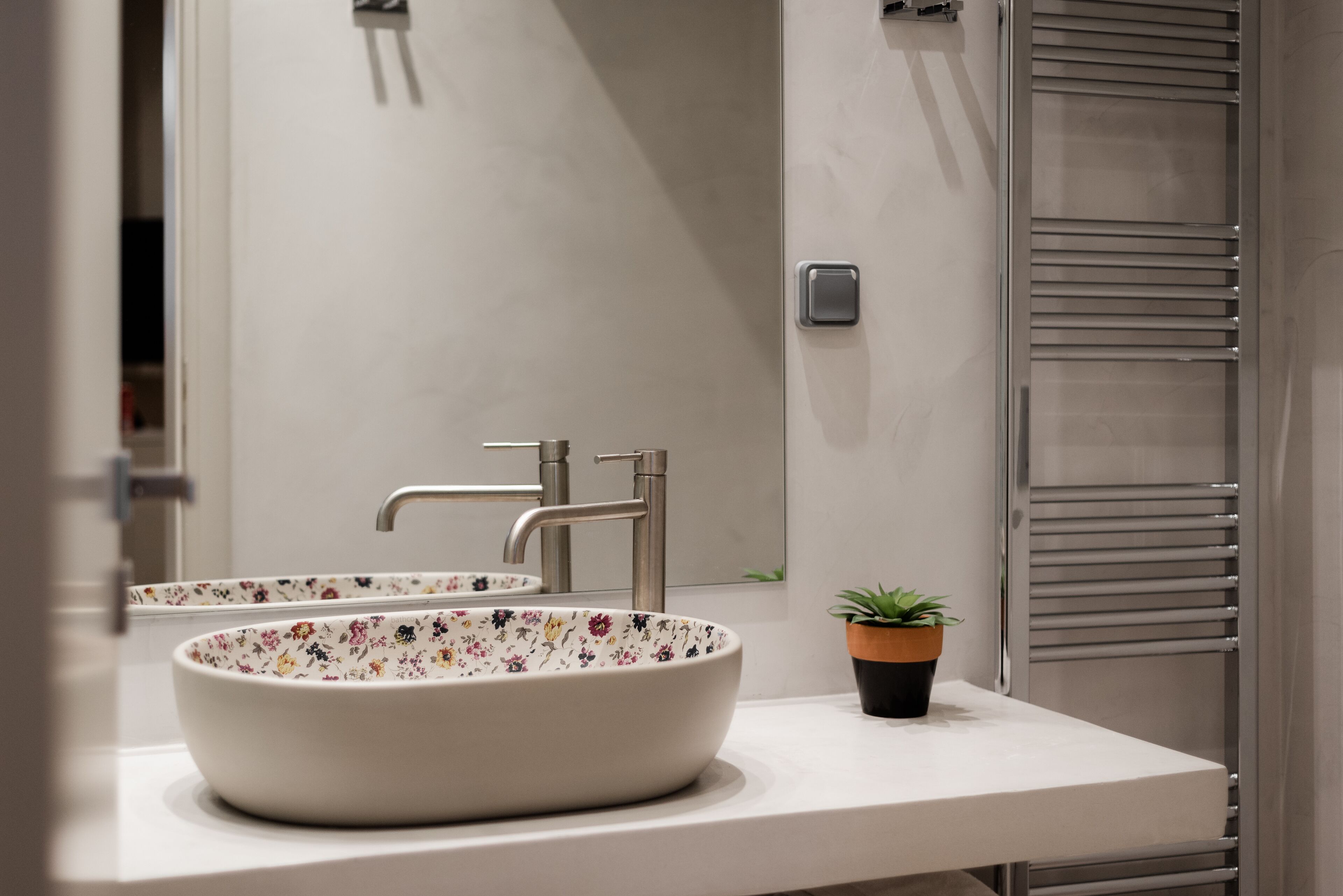 A bathroom with a white sink, a mirror, and a towel rack.