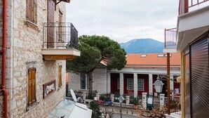 Una estrecha calle con edificios de piedra, mesas al aire libre y una montaña al fondo.