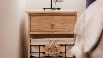 Una mesita de noche de madera con una lámpara, un cajón y dos cajas de almacenamiento etiquetadas