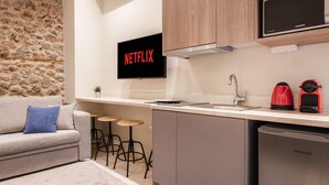 Una cocina moderna con pared de piedra, televisor de pantalla plana, cafetera y lavavajillas.