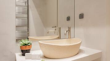 Un baño moderno con un lavabo grande y redondo, un espejo y un perchero para toallas.