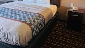 Une chambre d’hôtel avec un grand lit, une tête de lit, deux lampes fixées au mur et une petite table de chevet.