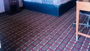 Une chambre d’hôtel avec un lit, une table de chevet, un bureau et une moquette à motifs.