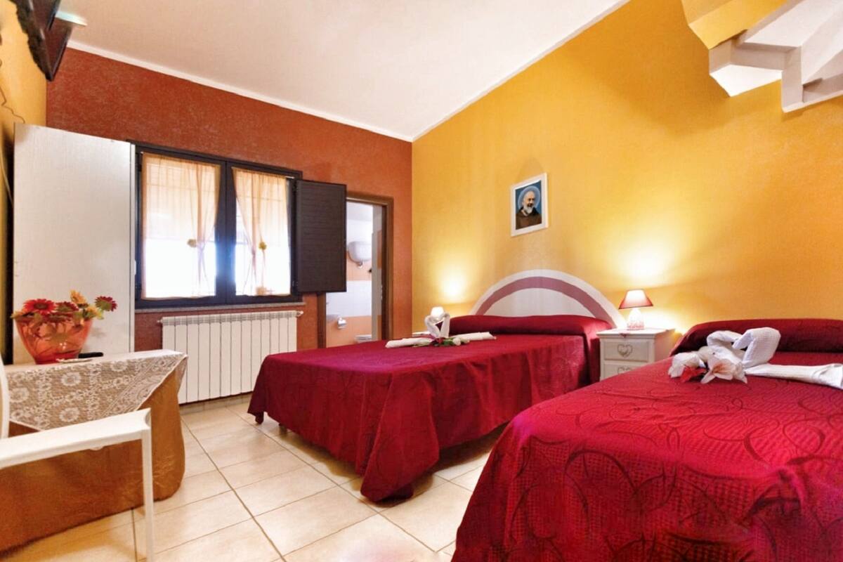 Ein Hotelzimmer mit zwei Betten, einem Schreibtisch und einem Fenster mit Vorhängen.