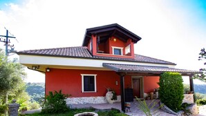 Ein zweistöckiges Haus mit roter Fassade, einem Ziegeldach und einem Steinkamin.