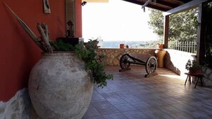 Eine Terrasse mit einem großen Blumentopf, einer Schubkarre und einer Steinmauer.