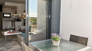 Een moderne keuken met een groot raam, een eethoek met een glazen tafel en een balkon met uitzicht.