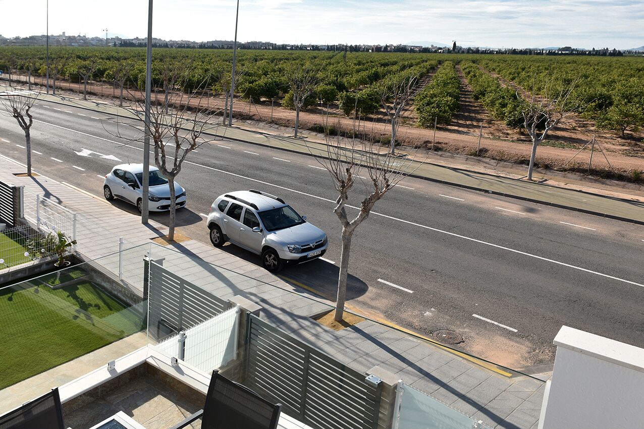 Un edificio moderno con un estacionamiento y un viñedo al fondo.
