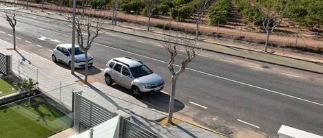 Un edificio moderno con un estacionamiento y un viñedo al fondo.