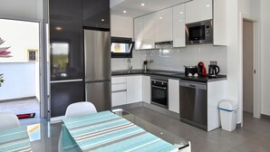 Een moderne keuken met roestvrijstalen apparatuur, een magnetron en een koffiezetapparaat.
