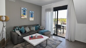 Een moderne woonkamer met een grijze bank, een witte salontafel en twee schilderijen aan de muur.
