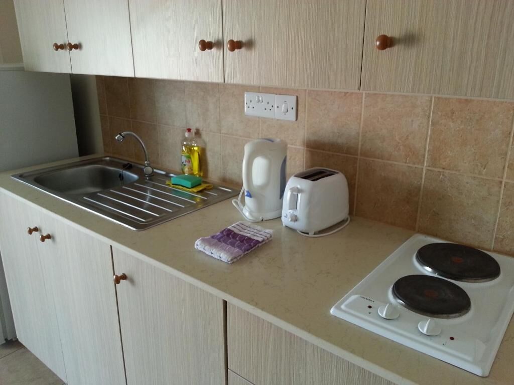 A kitchen with a sink, a toaster, a kettle, and a stove.