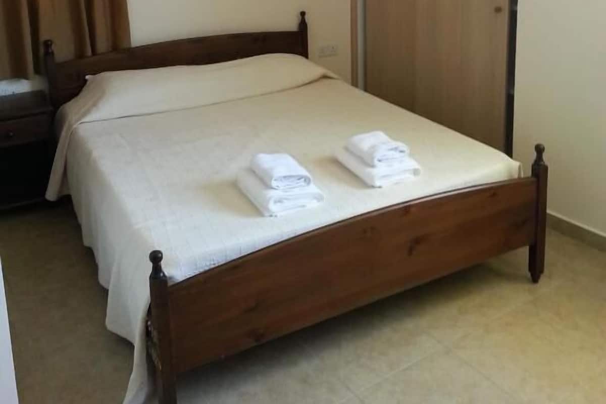 Una cama individual con estructura de madera, un armario y una mesita de noche.
