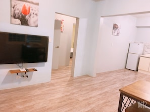 Ein modernes Wohnzimmer mit Flachbildfernseher, Holzboden und einer Essecke mit Tisch.