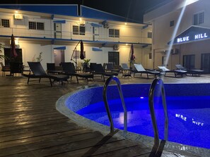 Zona de piscina con sillas de descanso y un letrero que dice 'BLUE HILL'.