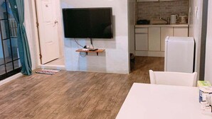 En kompakt bolig med spisebord, fjernsyn og tekøkken.