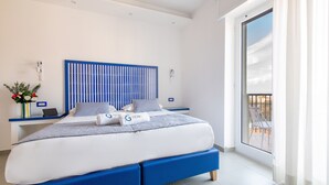 A modern hotel room with a large bed, a nightstand with a phone, a laptop, and a vase with flowers. - Al Campanile (Sant'Agnello)
