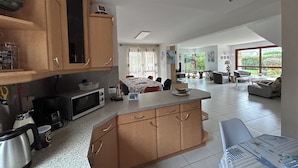 Una cocina amplia con armarios de madera y una isla grande, que da paso a un comedor con vistas al exterior.