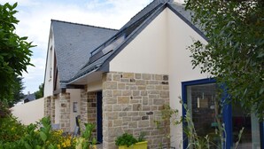 Una casa con fachada de piedra, una puerta azul y una pequeña mesa amarilla con plantas.