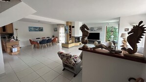 Un amplio salón con una mesa de comedor, una chimenea y una gran escultura de caballito de mar.