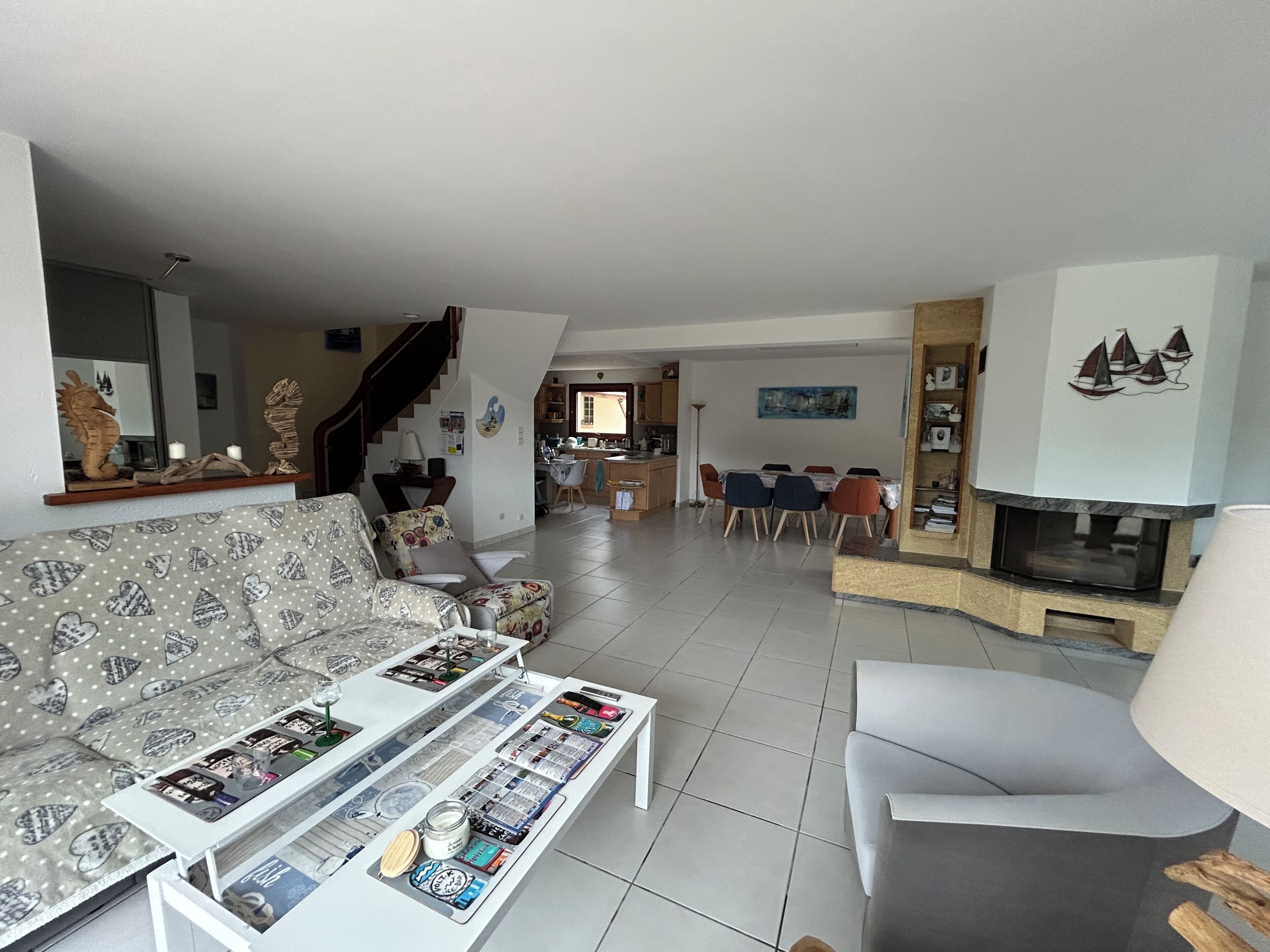 A living room with a sofa, coffee table, fireplace, and a dining area with chairs and a table.