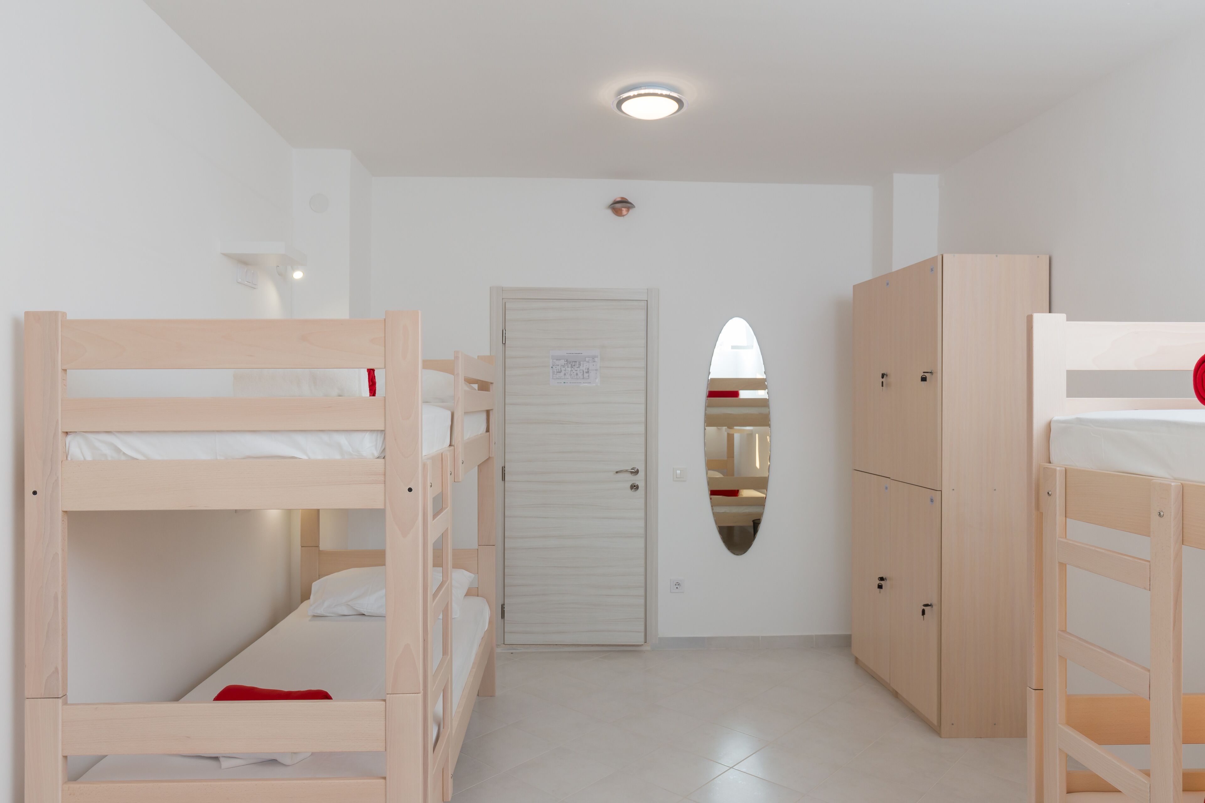 A room with bunk beds, a wardrobe, and a door with a mirror.