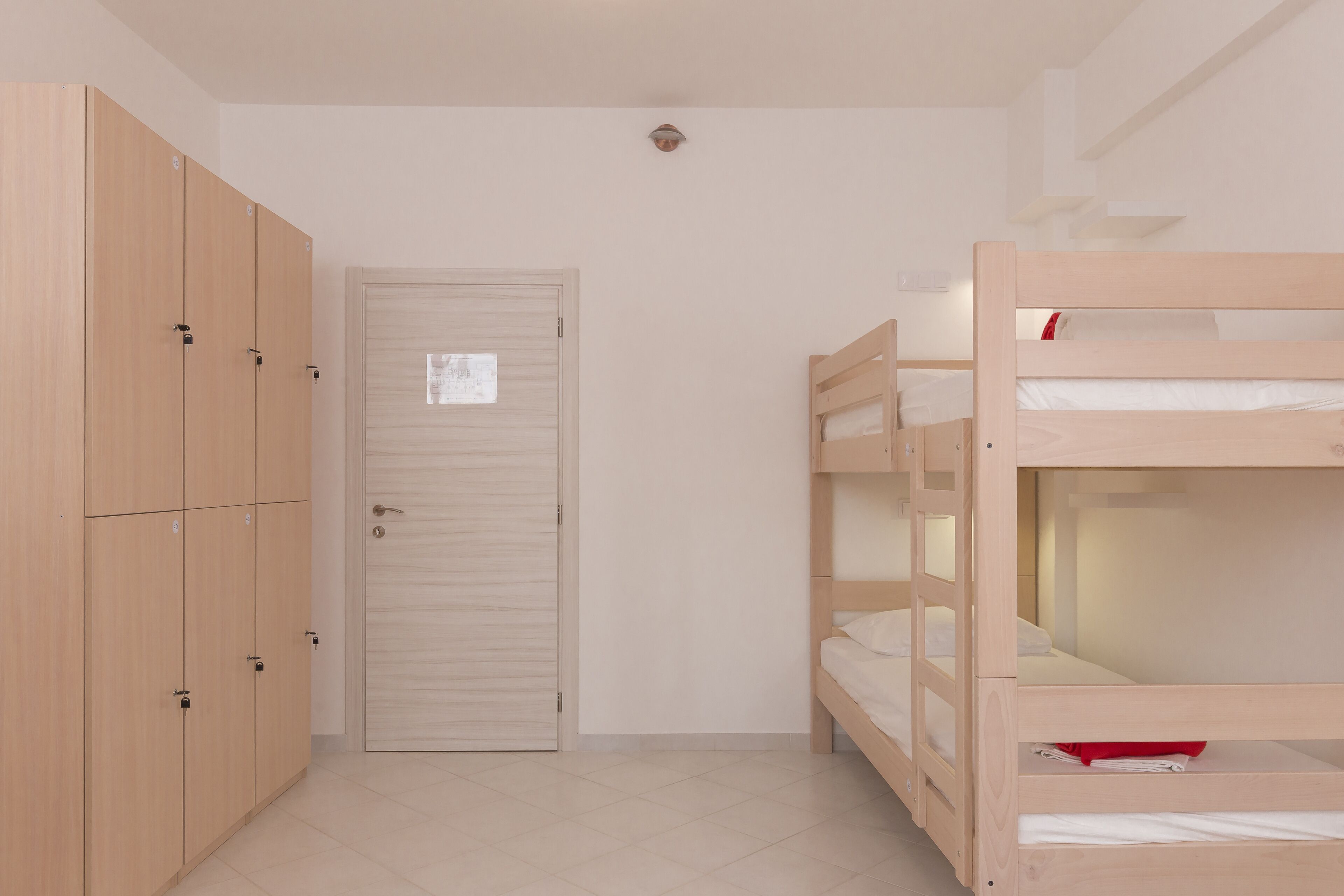 A room with a bunk bed, a wardrobe, and a door.