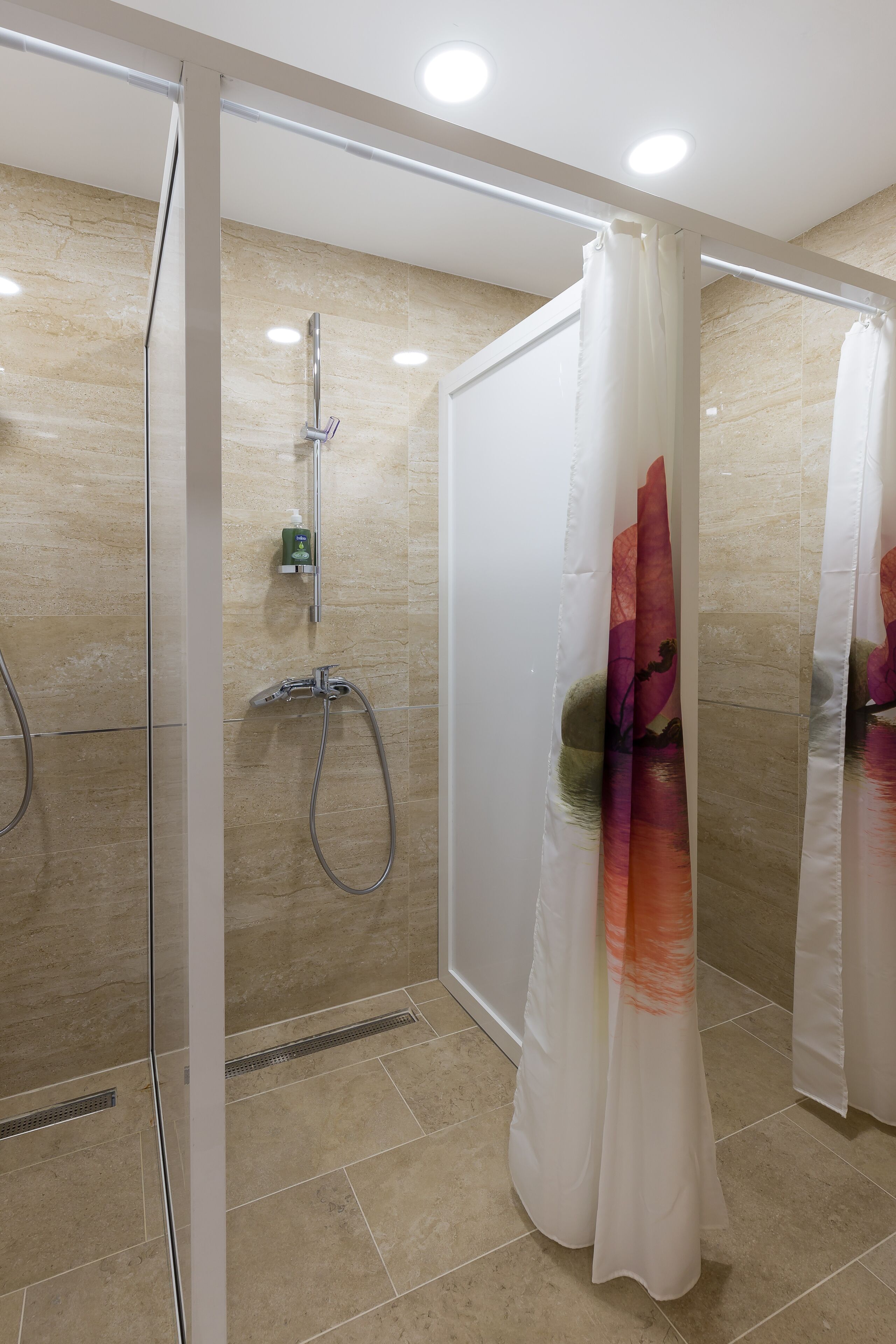 A modern shower with a glass door, a handheld showerhead, and a wall-mounted faucet.